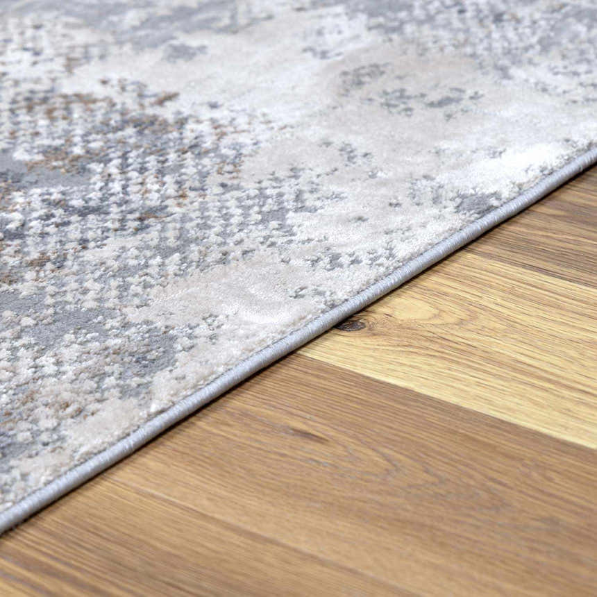 Close-up of the Ironwood Textured Luxe Rug showing charcoal, gray, and brown tones with a subtle, abstract pattern. Pile