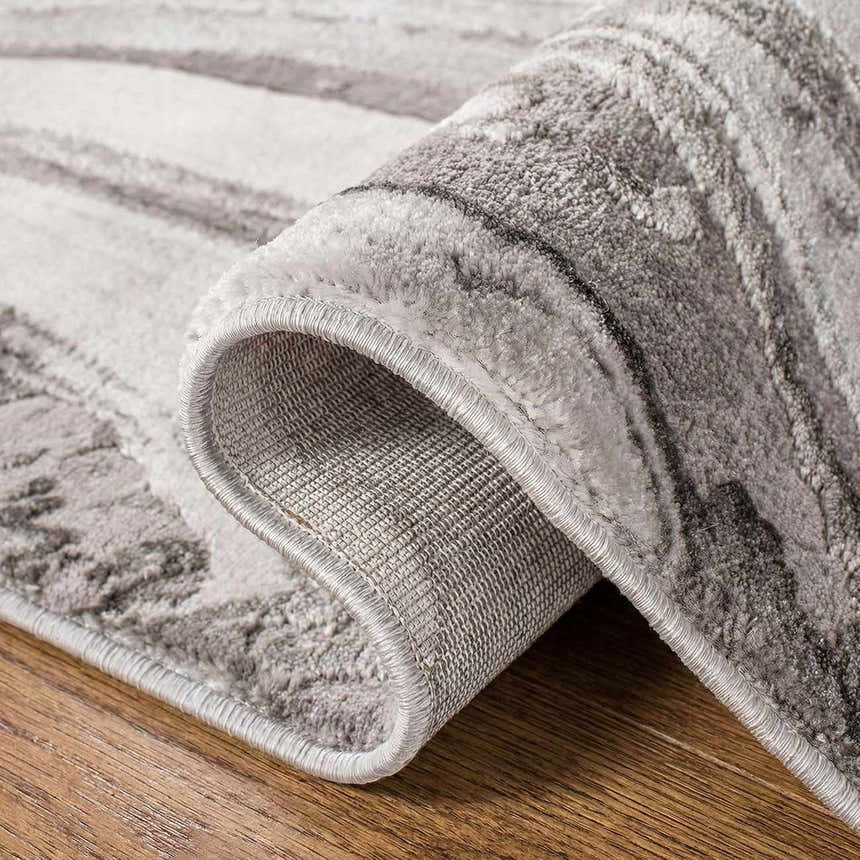 Close-up of the Itotia Marble Green Area Rug showing the contemporary silver gray pattern and machine woven construction. Fold