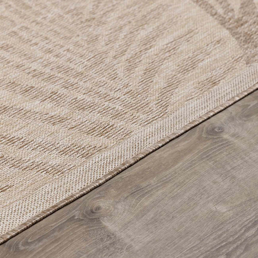Close-up of the Jens Area Rug showing a cream and tan geometric pattern and woven texture on a wood floor. Texture