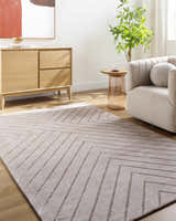 Living room scene with a Tavran Taupe rug, light wood floors, beige armchair, and cabinet with modern art. Roomscene-Rectangle