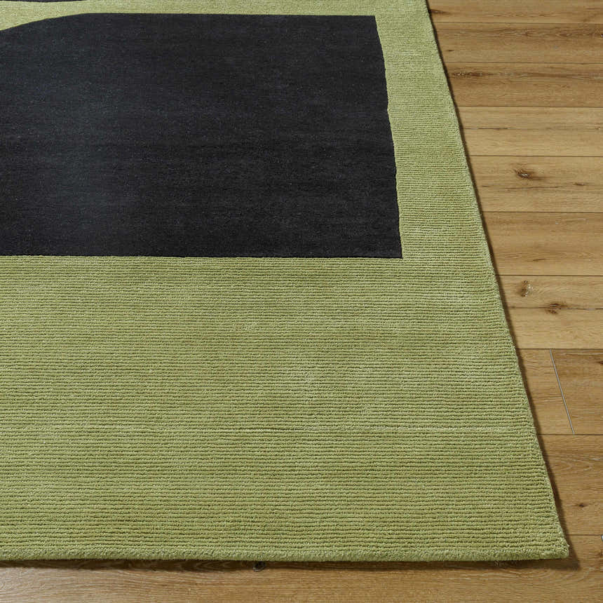 Close up of the Arvok Olive Green rug showing its charcoal block design, hand-tufted wool texture, and olive border on wood floors. Front
