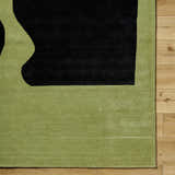 Close up of the Arvok Olive Green rug showing the charcoal block pattern and hand-tufted wool texture. Corner