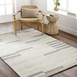Living room scene with Livabliss Granada Surya GND-2358 rug in beige, cream, and gray. Modern chair and side table on dark wood floors. Roomscene-Rectangle