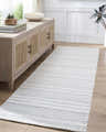 Living room scene with a Kendi Cream Area Rug, light wood floors, and a rattan cabinet. Roomscene-Runner