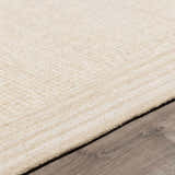 Close up of the hand-tufted Kayoko Ivory Area Rug showing its subtle pattern and texture on dark wood flooring. Pile