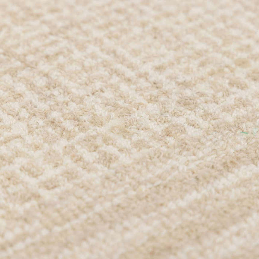 Close-up of the hand-tufted Kayoko Ivory Area Rug. Cream and off-white wool with subtle geometric pattern. Soft texture. Texture