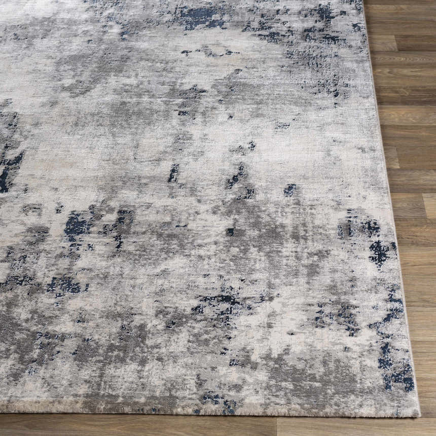 Close-up of Livabliss Aisha Surya AIS-2314 area rug. Abstract design in blue, charcoal, light gray, and off-white on wood floor. Front