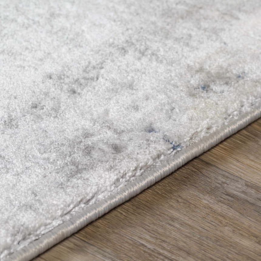 Close-up of the Livabliss Aisha rug showing its light gray, charcoal, and blue contemporary pattern and soft texture. Texture