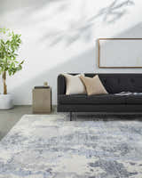 Living room scene with a charcoal sofa and the Keme Area Rug in charcoal, gray, and blue. Roomscene-Rectangle