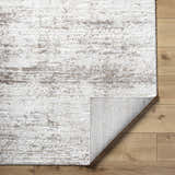 Close-up of the Kohaku Light Gray Area Rug showing its beige, ivory, and light brown abstract pattern and machine-woven texture. Fold