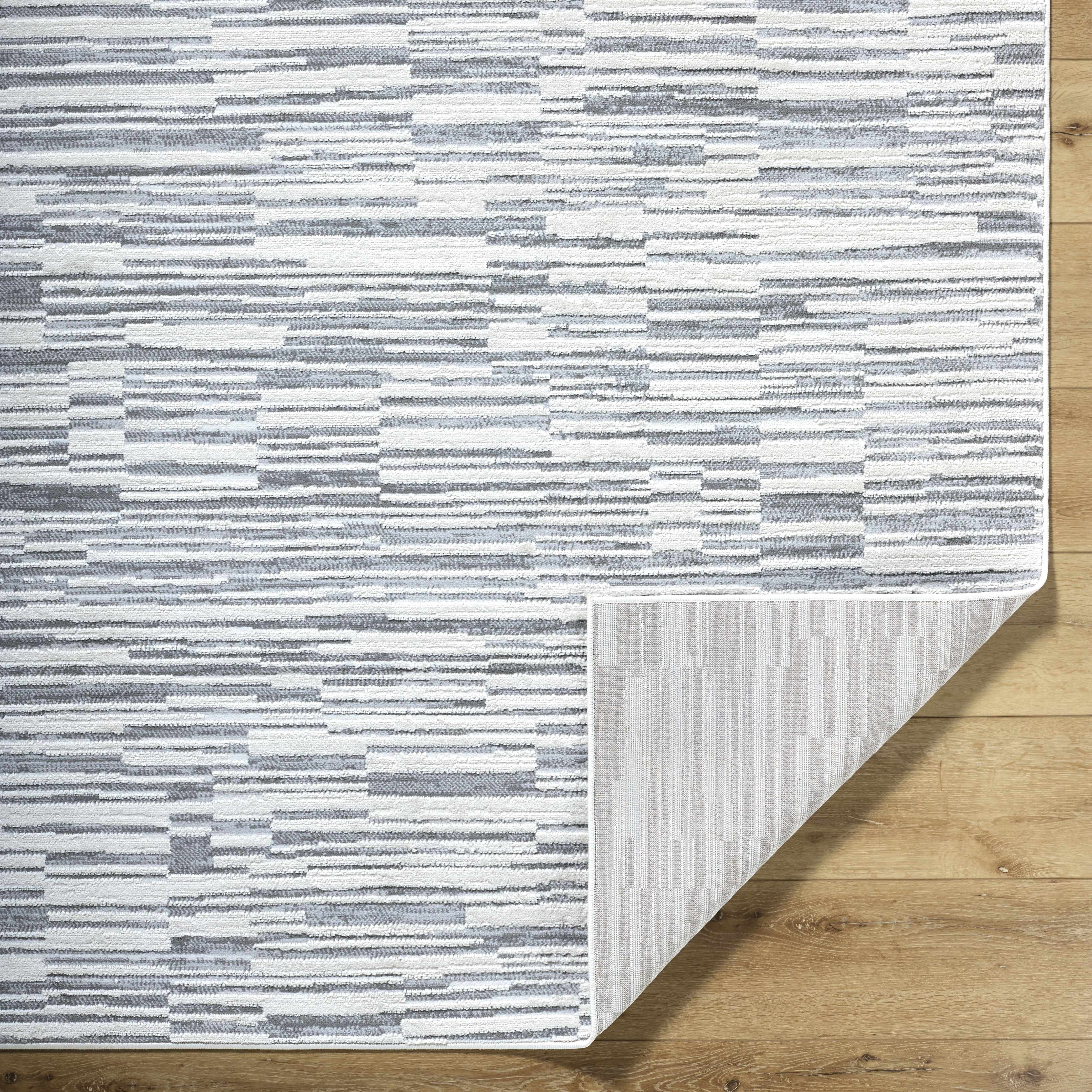 Folded section of Alexey Gray Broken-Striped Area Rug, displaying material thickness and weave. Contemporary Area Rug Backing  