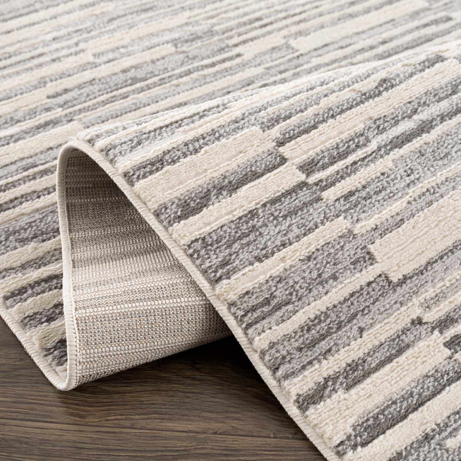 Folded section of Alexey Gray Broken-Striped Area Rug, displaying material thickness and weave. Contemporary Area Rug Backing  