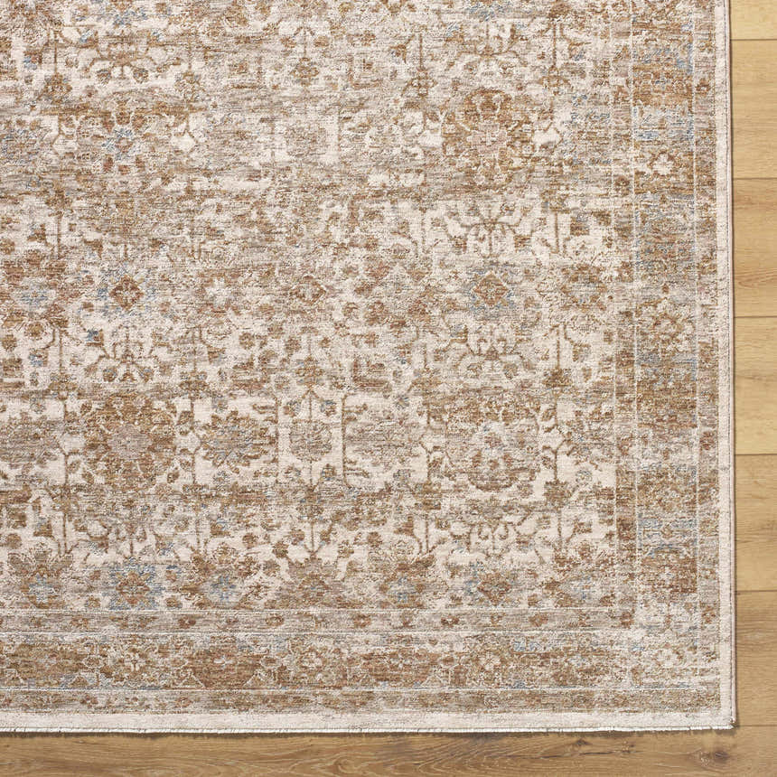 Close-up of the Andres Sage Area Rug. Traditional floral pattern in cream, tan, light brown, and blue colors. Corner
