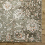 Close-up of the Limay Premium Wool Rug. Hand-knotted rug with a traditional floral pattern in olive, beige, and coral tones. Corner