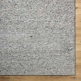 Close-up of the hand-tufted Winta Charcoal Wool Area Rug showing ash, gray, and silver gray tones and textured wool design. Corner