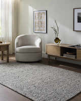 Living room scene with a Winta Charcoal Wool Area Rug, gray chair, and wood media console. Roomscene-Rectangle