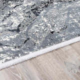 Close-up of Littleport Luxury Fringed Faux Silk Rug. Abstract black, charcoal, and gray pattern with fringed edge. Pile