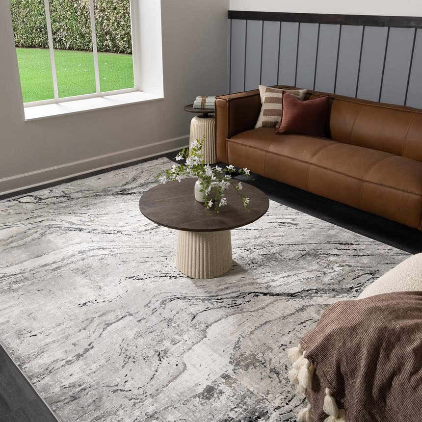 Living room scene with Littleport Luxury Fringed Faux Silk Rug in gray, black, and charcoal under a round coffee table. Roomscene-Rectangle