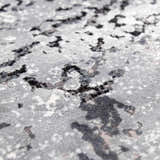 Close-up of the Littleport Luxury Fringed Faux Silk Rug. Abstract design in black, charcoal, gray, and light gray tones. Texture