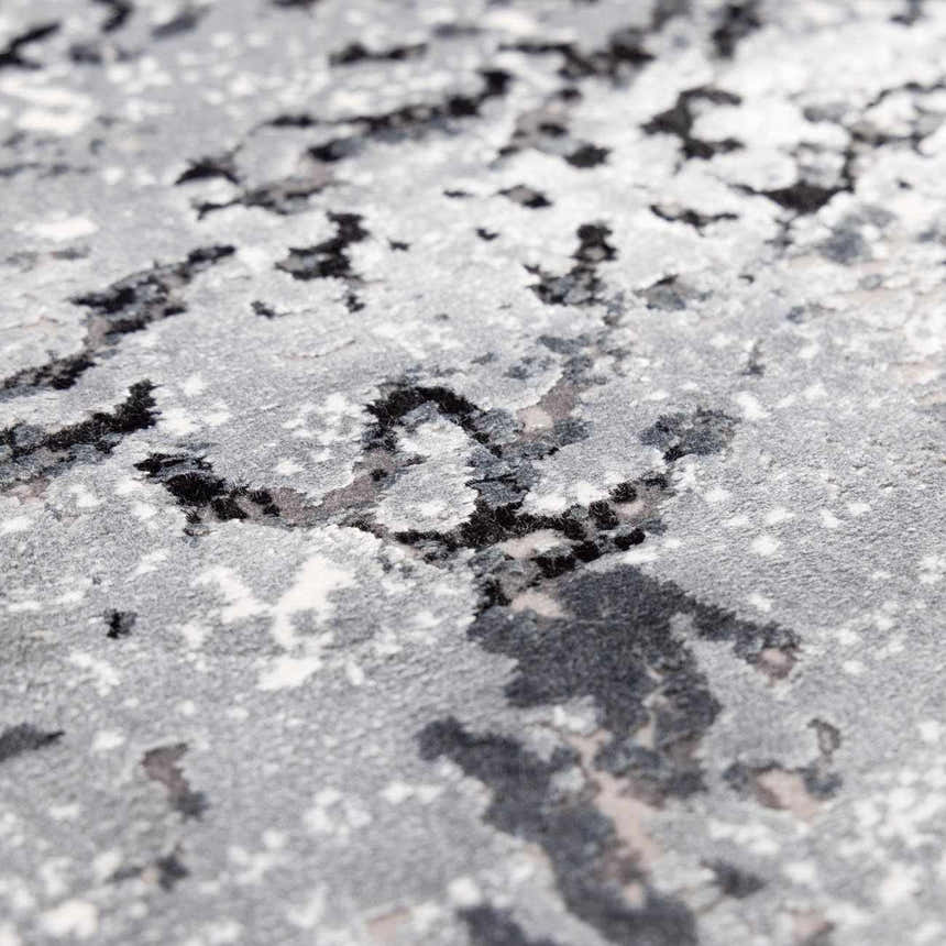 Close-up of the Littleport Luxury Fringed Faux Silk Rug. Abstract design in black, charcoal, gray, and light gray tones. Texture