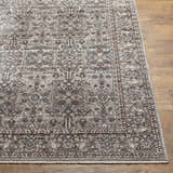 Close-up of the Lugo Luxe Area Rug showcasing its traditional floral pattern and tassel detail on a wood floor. Front