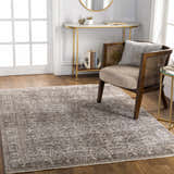 Living room scene with a charcoal Lugo Luxe Area Rug, wood chair, gold accents, and hardwood floors. Roomscene-Rectangle