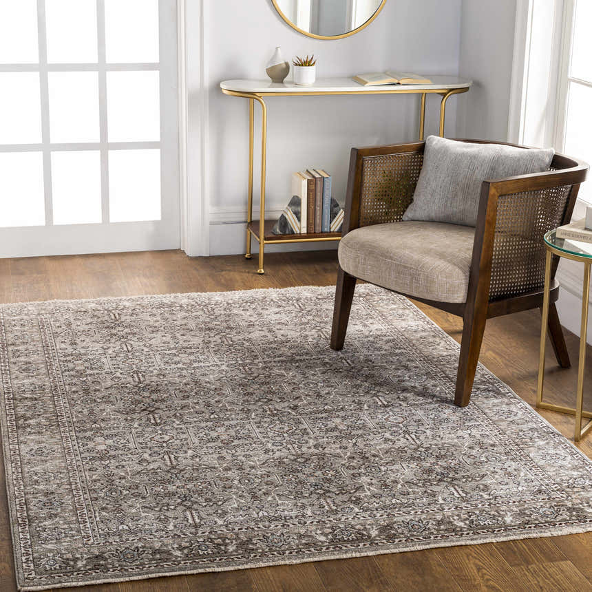 Living room scene with a charcoal Lugo Luxe Area Rug, wood chair, gold accents, and hardwood floors. Roomscene-Rectangle