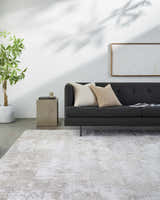 Living room scene with a gray sofa and the light gray Lumbia Distressed Embossed Area Rug on a concrete floor. Roomscene-Rectangle