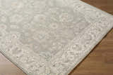 Close-up of the Alinae Area Rug. Farmhouse style rug in cream, green, and tan with a traditional floral pattern. Corner