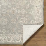 Close up of the Alinae Area Rug showing a traditional floral pattern in cream, green, and slate blue on hardwood floors. Fold