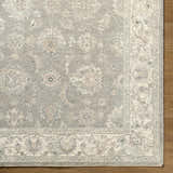 Close up of the Alinae Area Rug showing cream, green, and slate blue floral pattern and traditional design. Corner