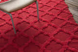 Close-up of the red Marilla Area Rug showing its shag texture and geometric trellis pattern, styled with a chair. Styleshot
