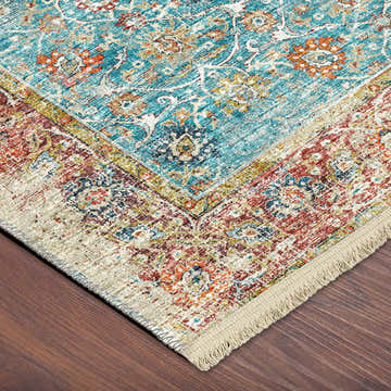 Close-up of the teal, gold, and paprika Dalyn Marbella rug with a traditional Mediterranean pattern and fringe.