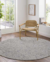 Light-filled room with round Melianna Gray Blue rug under a woven chair. Farmhouse style with wood floors. Roomscene-Round