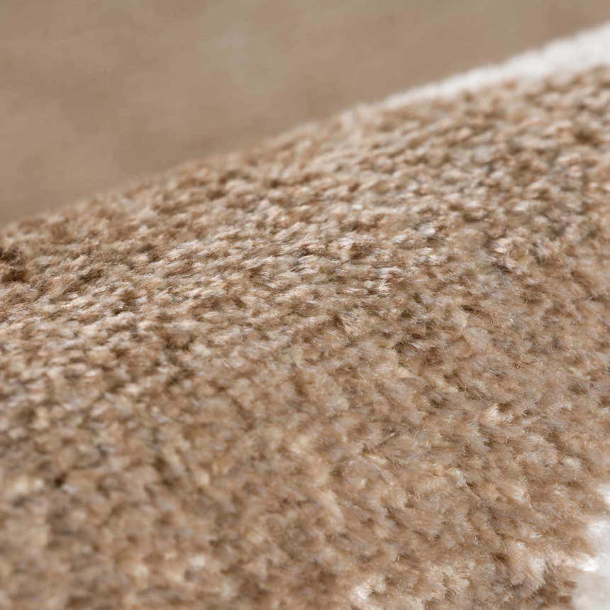 Close-up of the plush texture of the Ulric Brown Diamond Washable Area Rug, showing brown and cream fibers. Fold