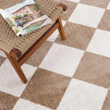 Close-up of the Ulric Brown Diamond Washable Area Rug featuring a brown and cream checkerboard pattern and woven texture. Styleshot