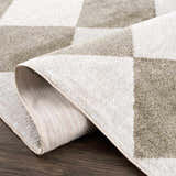 Close-up of the Ulric Green Diamond Washable Area Rug, showing cream and green diamond pattern and woven texture. Fold