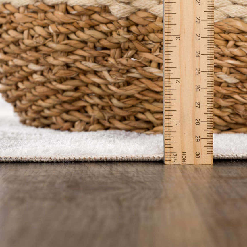 Close-up of the Ulric Light Gray Diamond Washable Area Rug showing pile height with a ruler and a wicker basket. Pile
