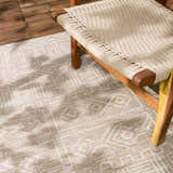 Close-up of the Epson Dark Beige Indoor & Outdoor Area Rug with geometric pattern and woven texture, paired with a wooden chair. Styleshot