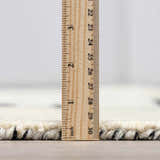 Close-up of the Brooklyn Modern Hand Tufted Wool Area Rug showing pile height with a ruler. Cream and black wool texture. Pile