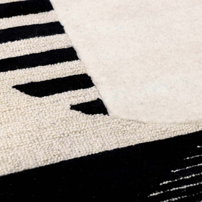 Close-up of the hand-tufted Brooklyn Modern wool rug. Features a geometric design in black and cream with a textured pile. Texture