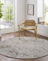 Bright room scene with round Nurit Sage rug, woven chair, wood floors, and natural light. Roomscene-Round