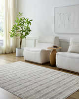 Living room scene with the Nuhad Area Rug, light wood floors, white chairs, side table, and plant. Roomscene-Rectangle