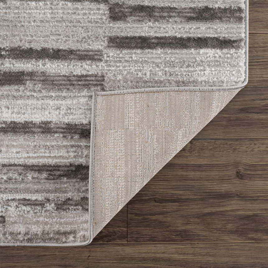 Close-up of Arissa Broken-Striped Area Rug showing black, gray, and white geometric pattern and rug backing. Fold