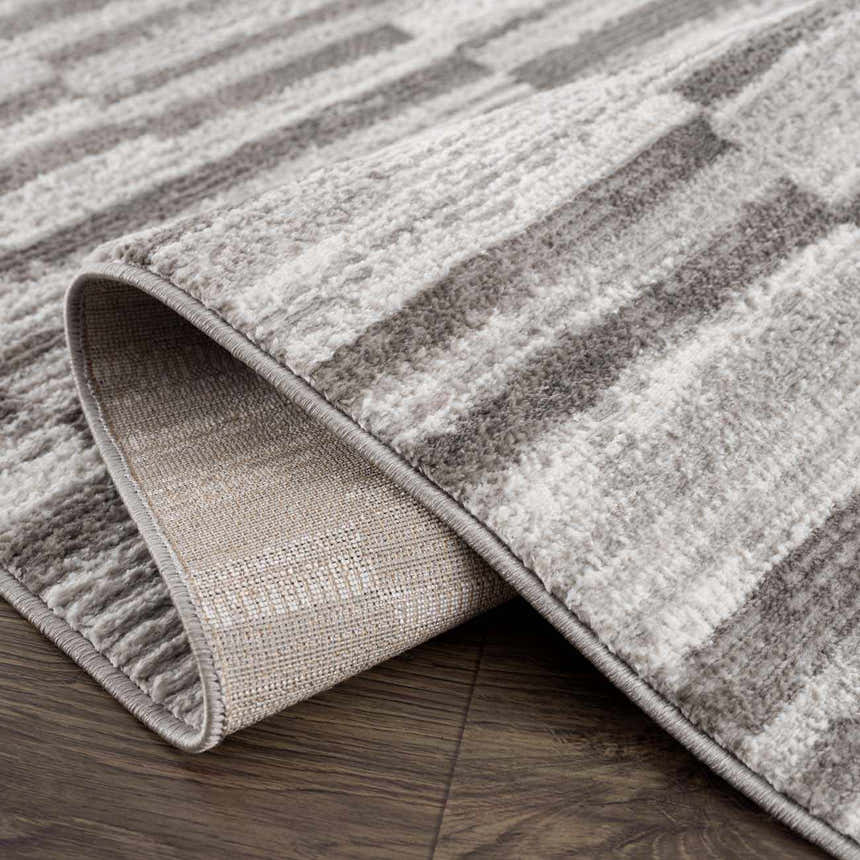 Close-up of the Arissa Broken-Striped Area Rug showing its gray, white, and black geometric pattern and machine-woven construction. Fold