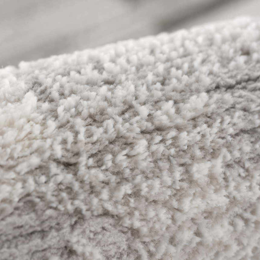 Close-up of the Arissa Broken-Striped Area Rug showing its plush, soft texture in shades of white, gray, and black. Texture