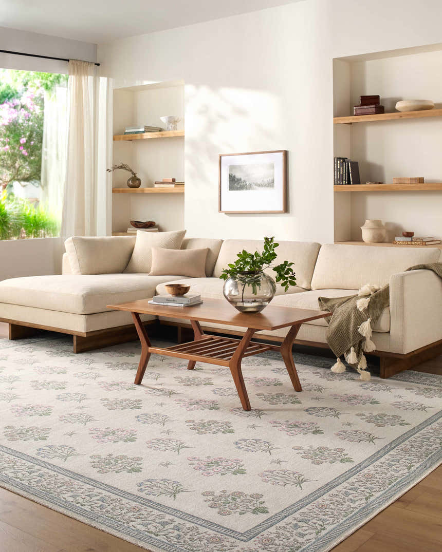 Living room scene with a neutral sofa and Aquene Ivory Washable Area Rug featuring blush, sage, and sky blue floral pattern. Roomscene-Rectangle