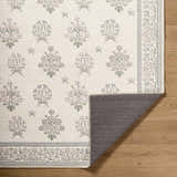 Close-up of the Aquene Ivory Washable Area Rug showing floral pattern in blush, sage, and sky blue on an ivory background. Fold