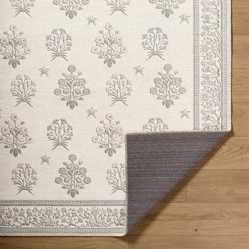 Close-up of the Aquene Ivory Washable Area Rug showing floral pattern in blush, sage, and sky blue on an ivory background. Fold