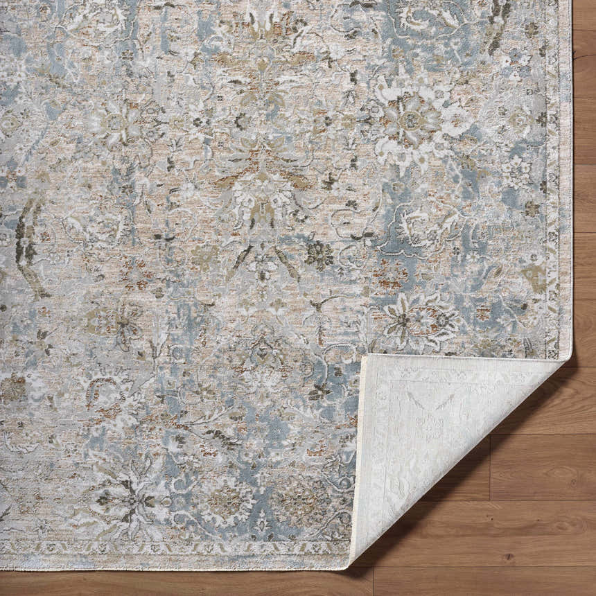 Close-up of the Nasir Thick Luxe Boutique Rug. Features a traditional floral pattern in charcoal, cream, light brown, and light gray. Fold